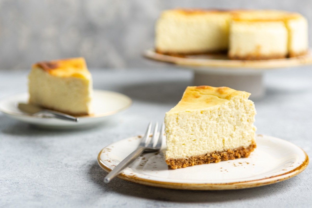 Zwei Stücke Käsekuchen mit Mascarpone auf zwei Tellern. Im Hintergrund ist der restliche Kuchen zu sehen.