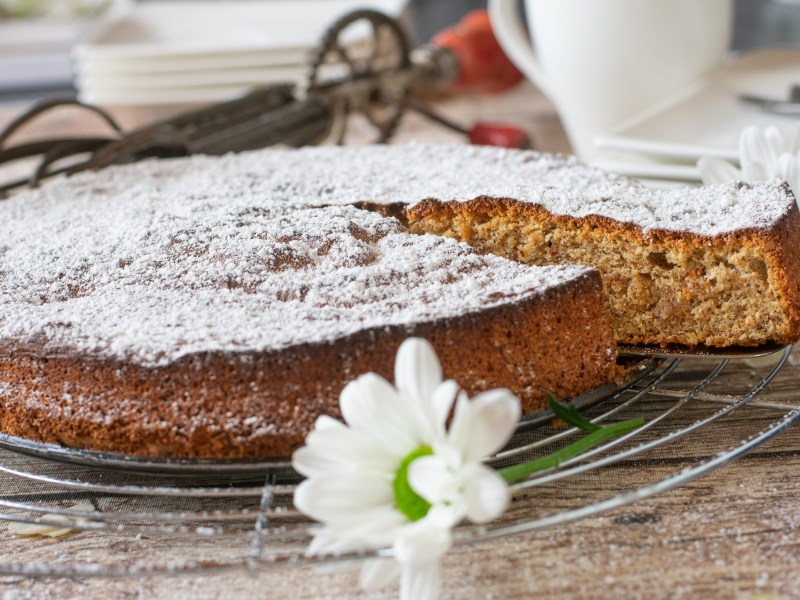 Abkühlgitter mit mallorquinischem Mandelkuchen und einer Blume im Vordergrund.