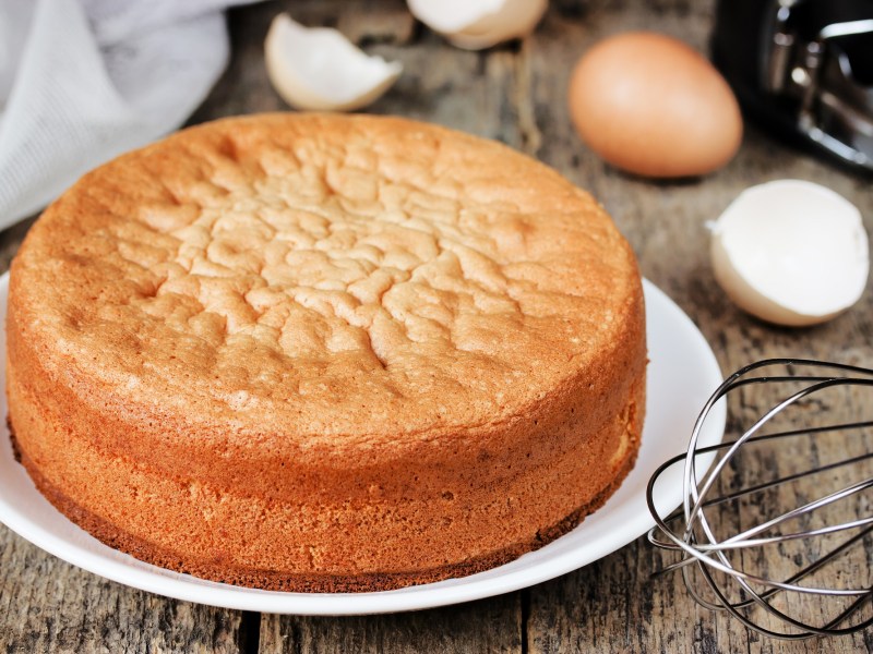 Marzipankuchen aus zwei Zutaten auf einem weißen Teller. Dahinter liegen Eierschalen und ein Schneebesen.