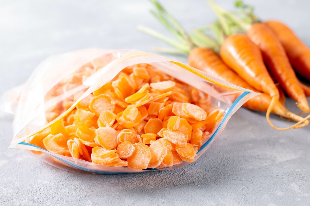 Möhren einfrieren: eine Ziplock-Tüte mit eingefroreren Möhrenscheiben, daneben frische Karotten.