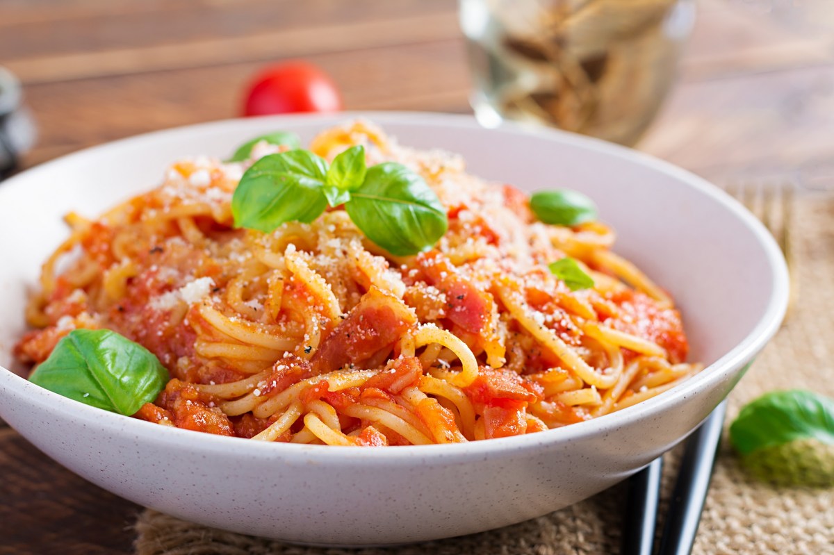 Ein Teller Nudeln mit Tomaten-Frischkäse-Soße mit Parmesan und Basilikum, Nahsicht.