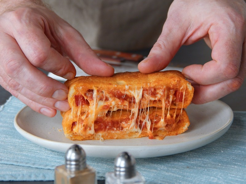 Pizzatoast-Taschen auf einem Teller, gefüllt mit Käse und Tomatensoße.
