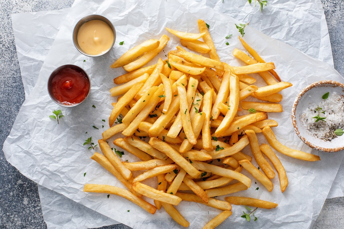 Pommes aufwärmen: Eine Portion Pommes mit Dips liegt auf Backpapier.