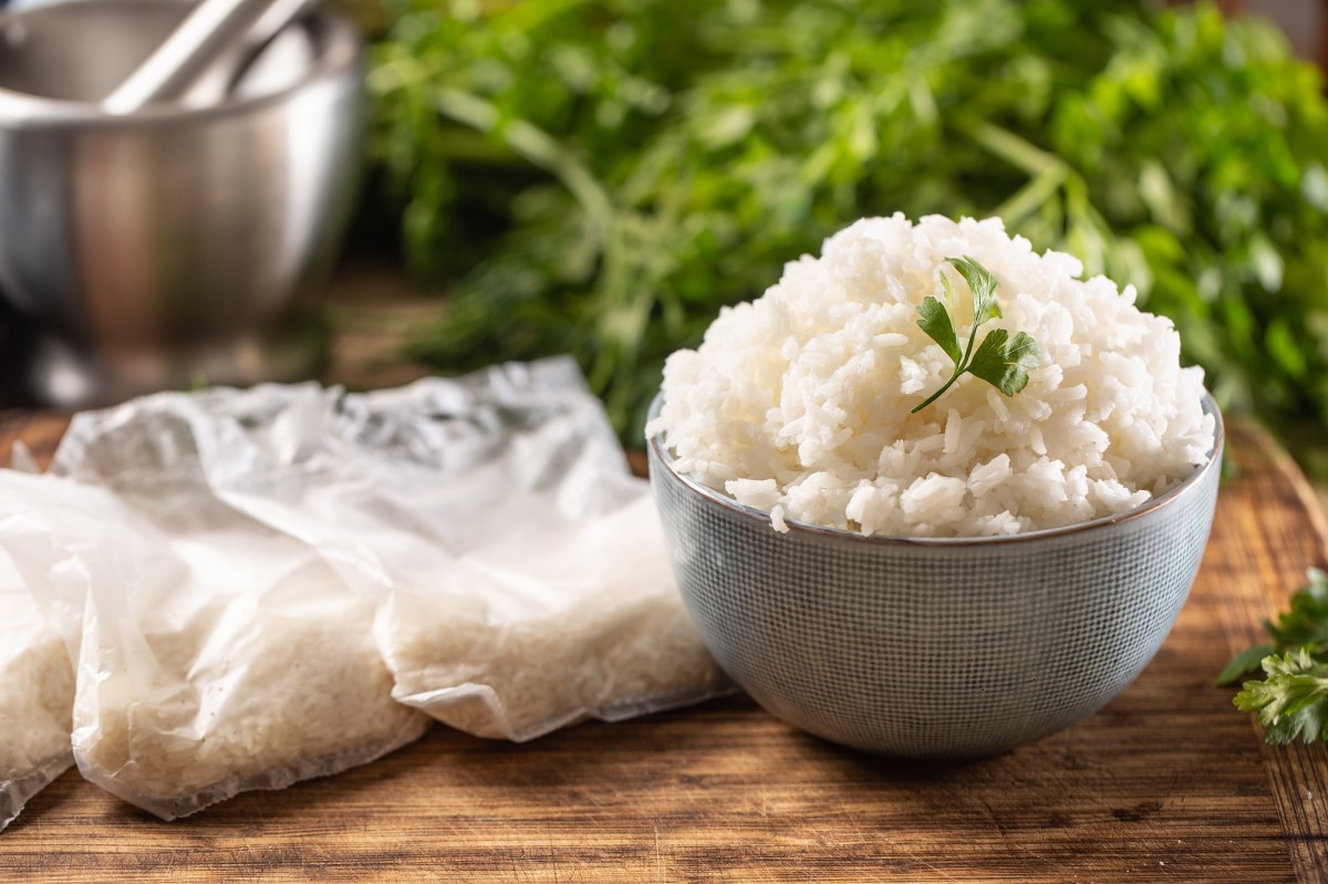 Reis einfrieren: eine Schüssel Reis, daneben Reisbeutel, im Hintergrund Kräuter.