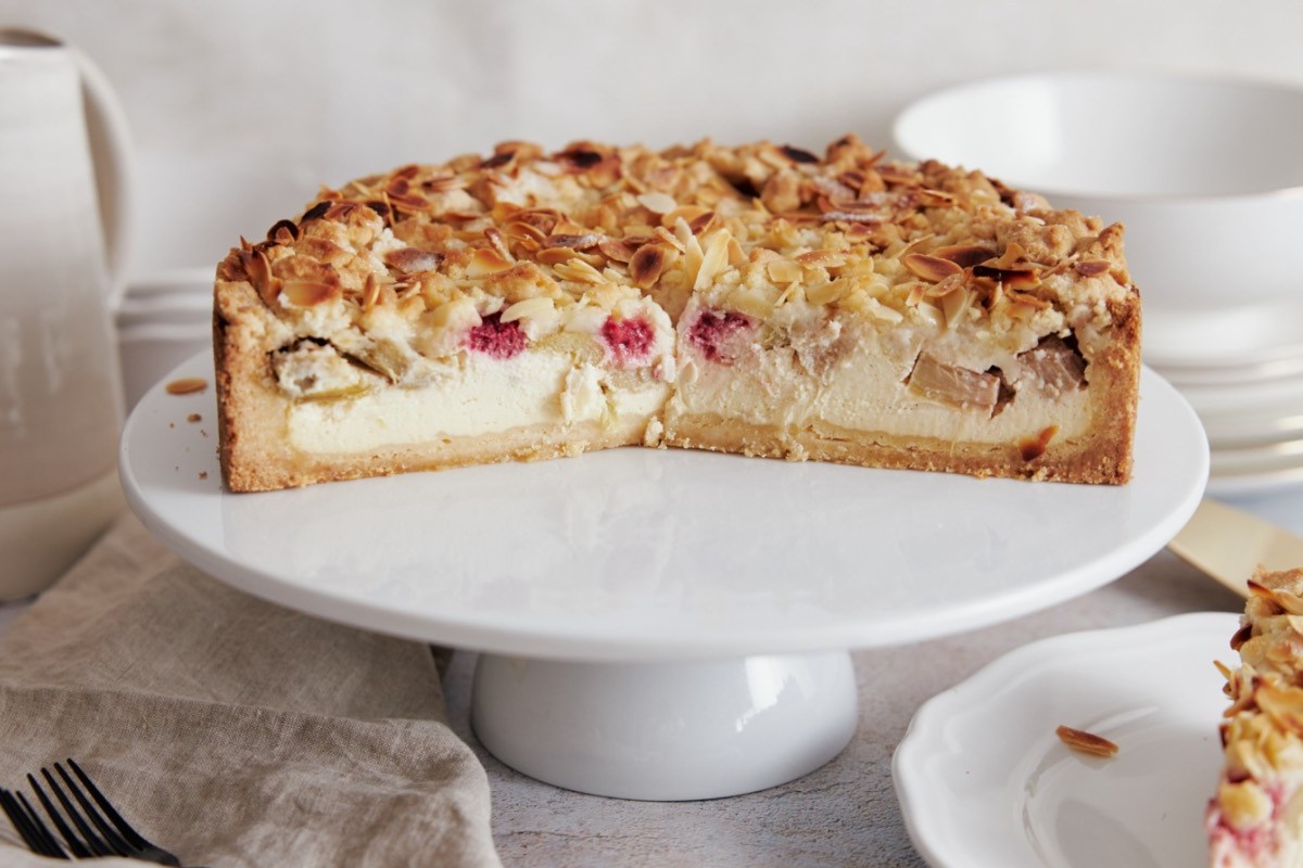 Ein halber Rhabarber-Käsekuchen auf einer Toretenplatte.