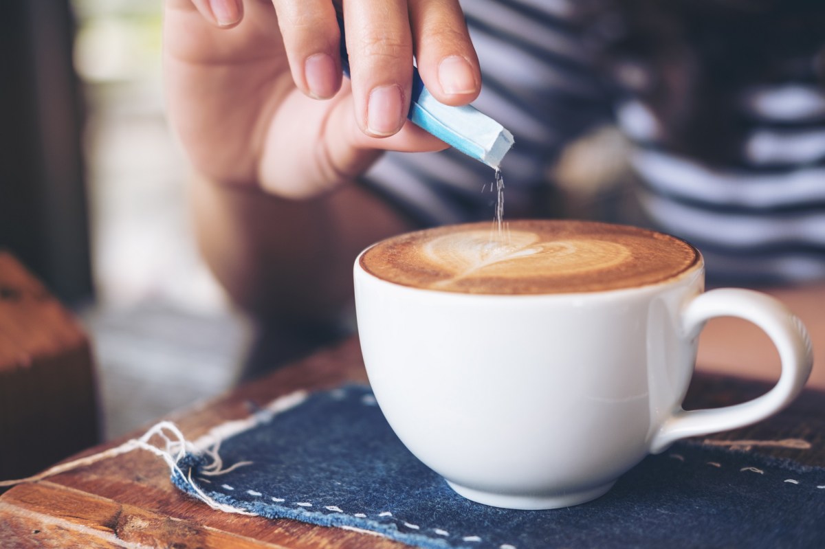 Salz im Kaffee: Eine Frau streut etwas Salz in eine Tasse Kaffee.