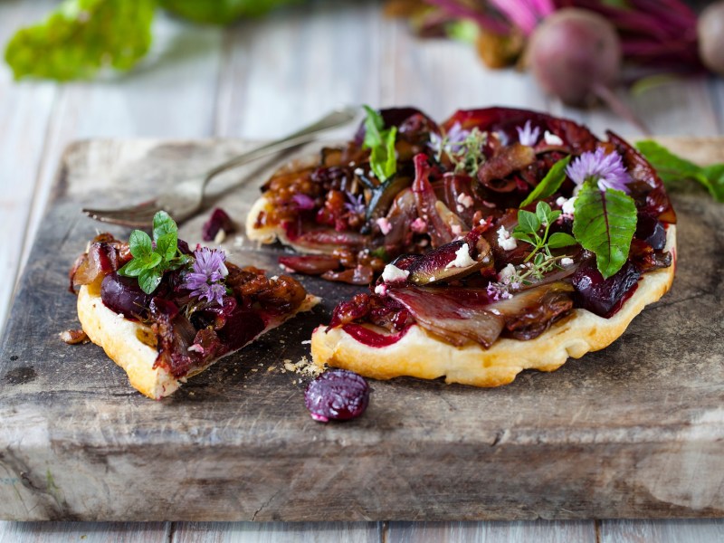 Die Schalotten-Tarte-Tatin, dekoriert mit Salat und essbaren Blumen.