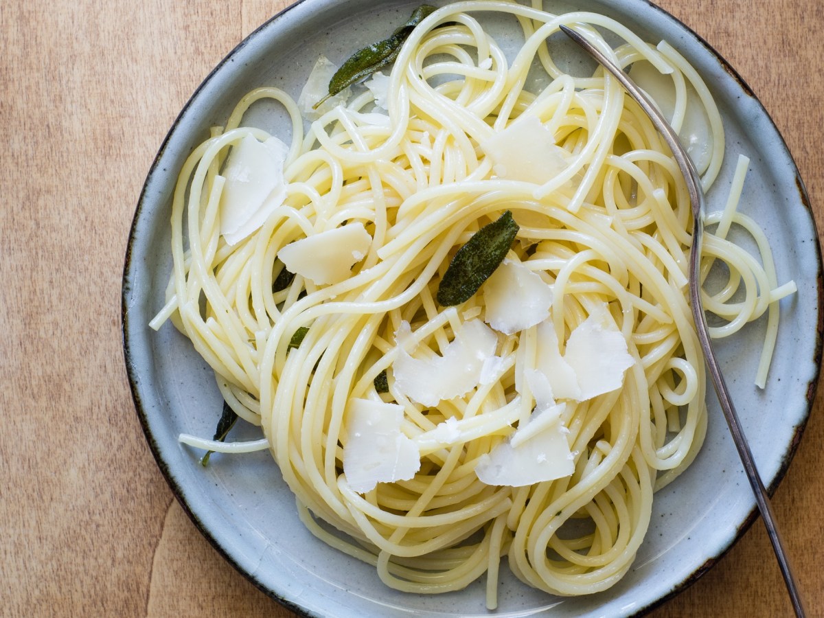 Teller mit Spaghetti mit Salbeibutter auf Holztisch
