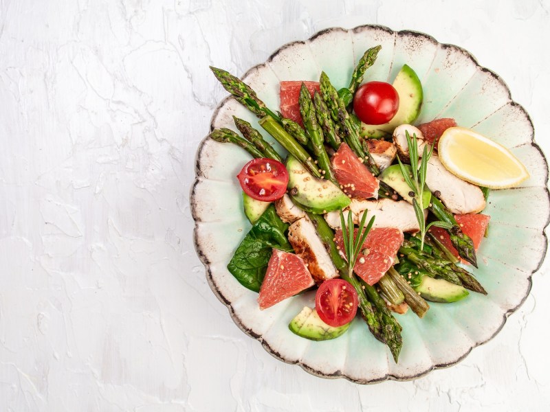 Spargel-Grapefruit-Salat mit Hähnchenbrust auf einem mintgrünen Teller.