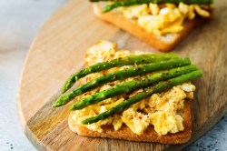 Spargel-Toast mit Rührei auf einem Holzbrett