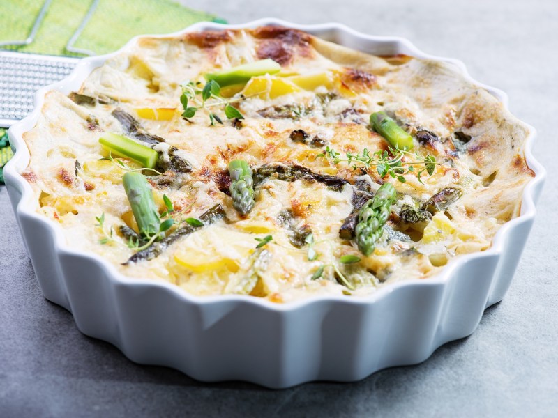 Auflaufform mit Spargel-Auflauf mit Kartoffeln auf hellem Tisch