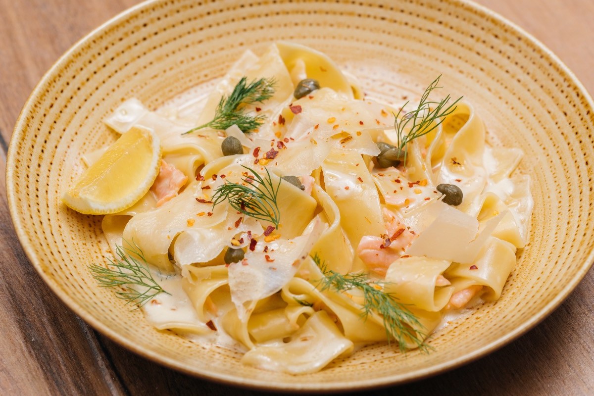 Eine Portion Tagliatelle al Salmone auf einem beigen Teller.