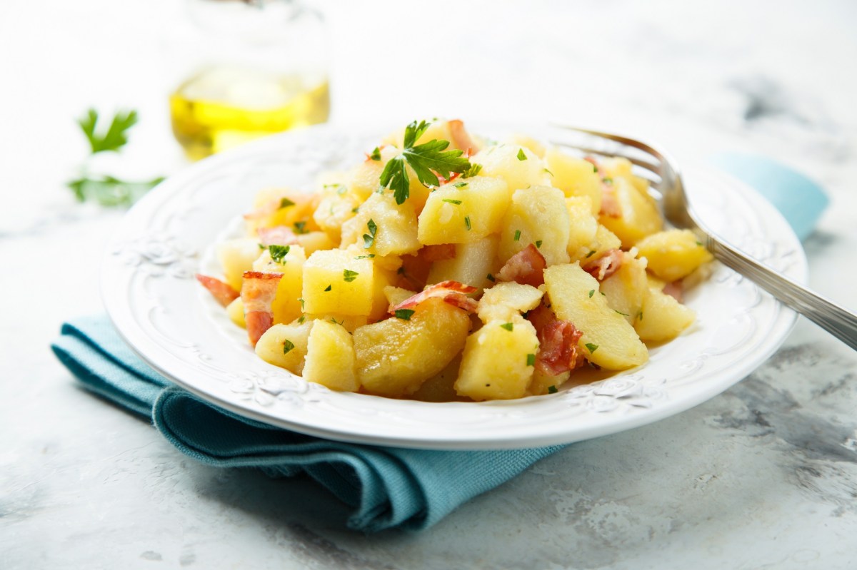 Warmer Kartoffelsalat auf weißem Teller