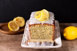 Ein angeschnittener und dekorierter Zitronen-Mohnkuchen mit Olivenöl.