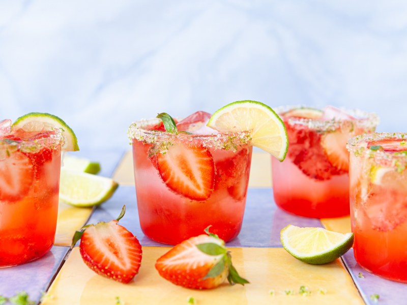 Alkoholfreie Erdbeerbowle in vier Gläsern, garniert mit Erdbeeren und Limetten.
