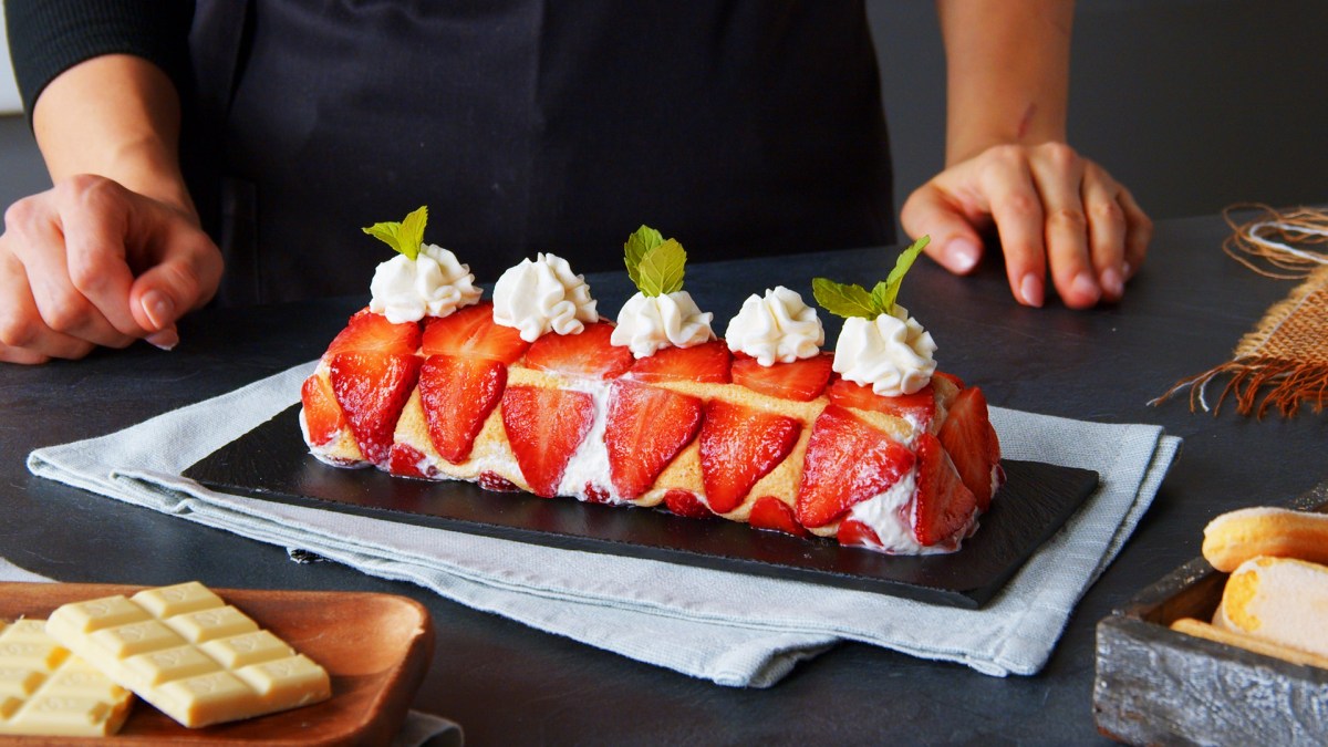 Einfache Erdbeer-Biskuitrolle dekoriert mit Sahnetupfen.
