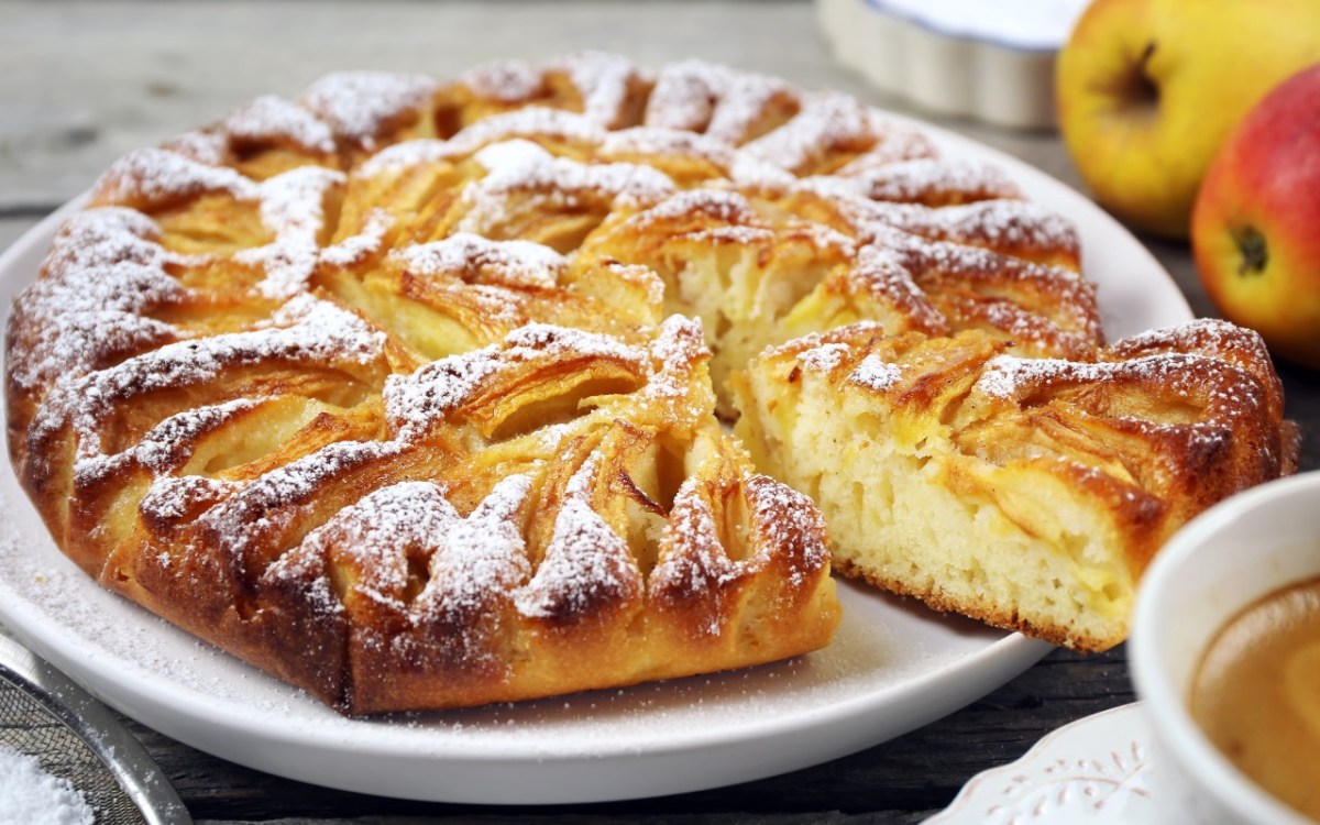 Ein Elsässer Apfelkuchen mit Puderzucker auf einem Teller.