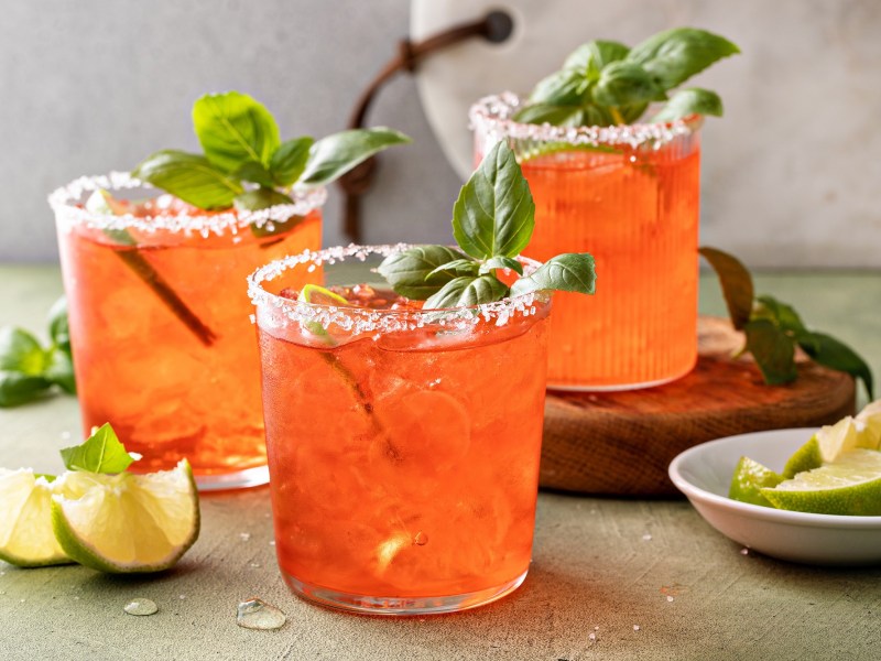 Drei Gläser mit Erdbeer-Basilikum-Margarita und Limettenspalten