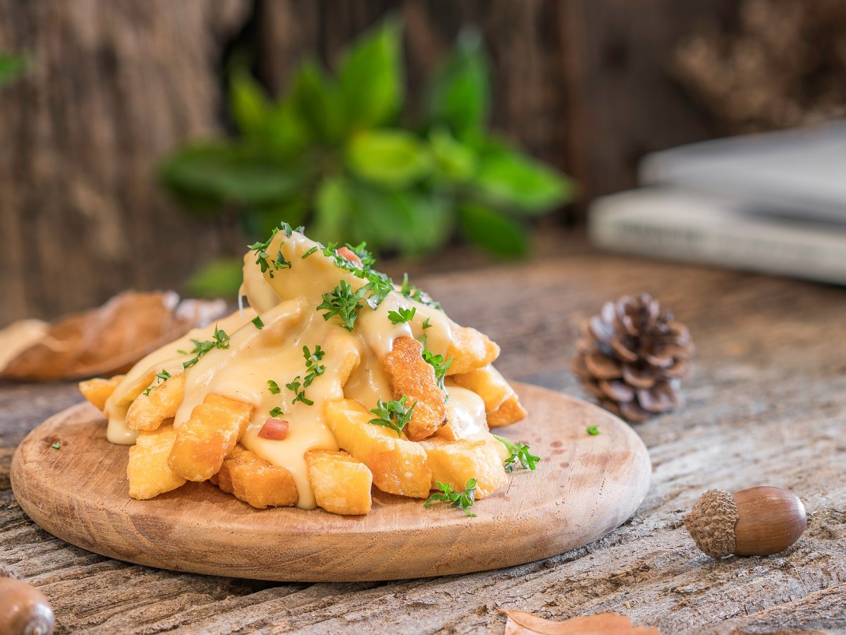 Käse-Pommes auf einem Brett, mit Petersilie bestreut.