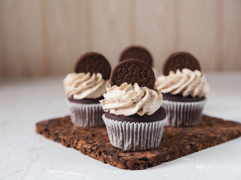 Oreo-Cupcakes mit einem Keks verziert auf einem Brett.