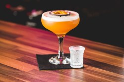 ein Glas Pornstar Martini garniert mit Passionsfruch, daneben ein Shotglas.