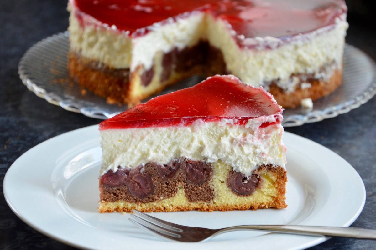 Ein Stück Rotkäppchen-Kuchen auf einem Teller. Im Hintergrund der restliche Kuchen.