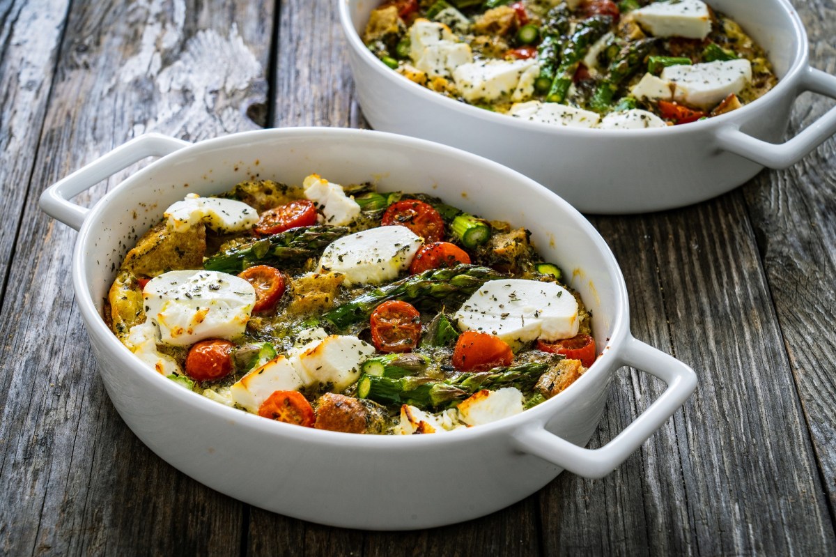 zwei Auflaufformen mit Spargel-Feta-Auflauf mit Kartoffeln und Tomaten.