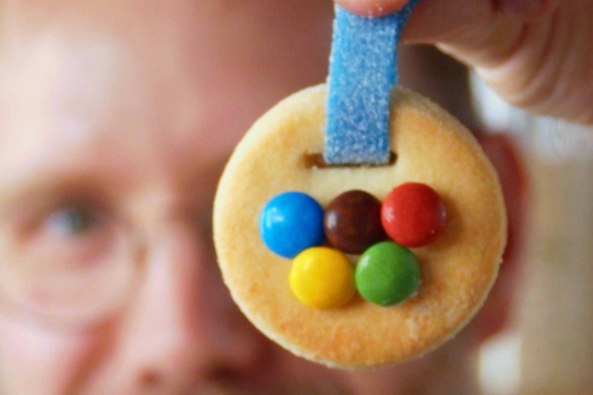 Medaillen-Keks backen: Jemand hält eine Medaille aus Keksteig hoch.