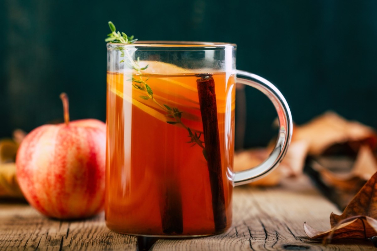 Eine Tasse selbstgemachter Apfeltee. Dahinter Zutaten.