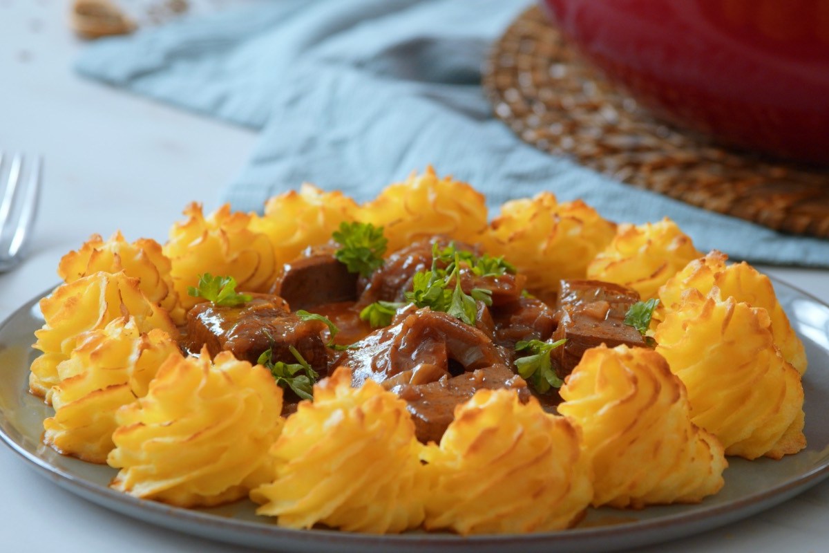 Ein Teller Tofu-Gulasch mit Herzogin-Kartoffeln.