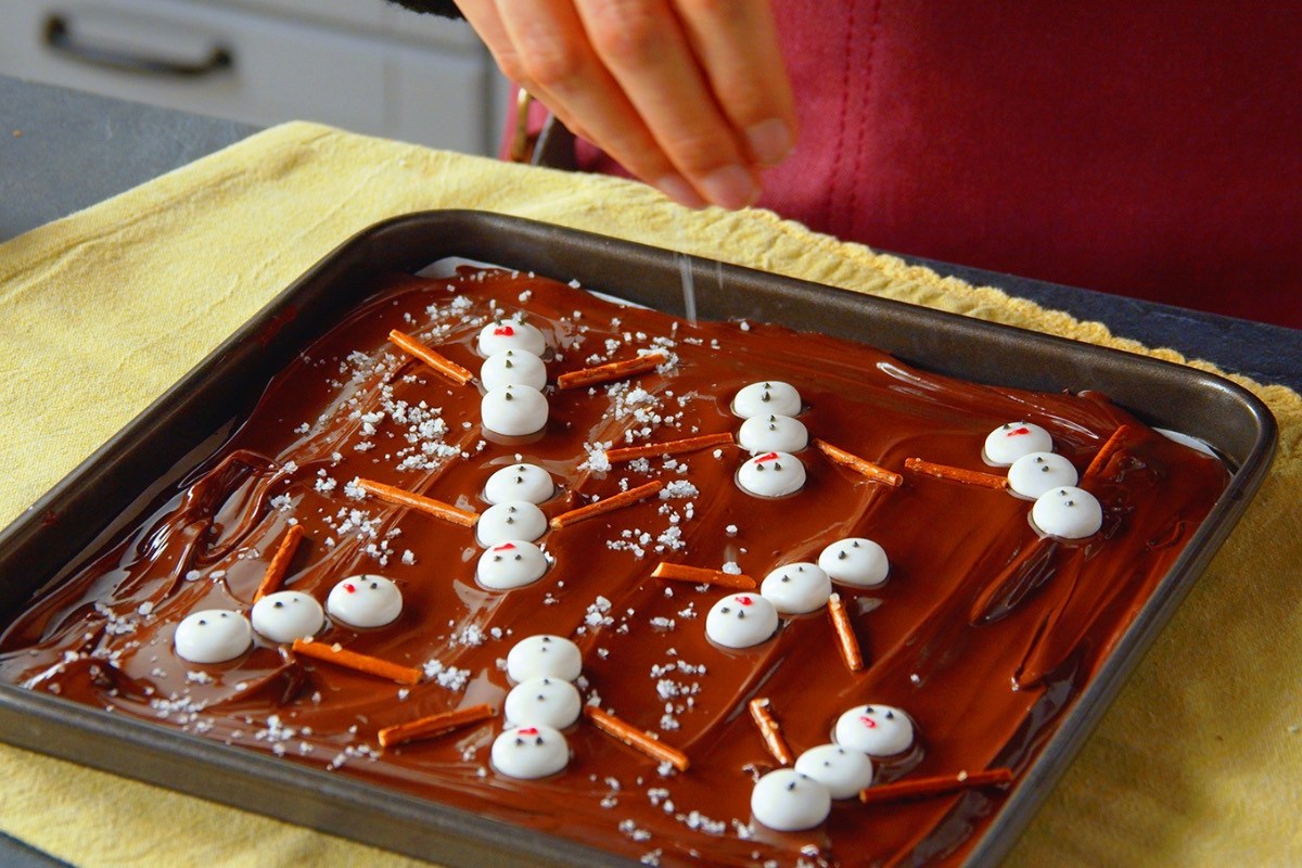 Bruchschokolade mit Schneemännern auf einem Blech.