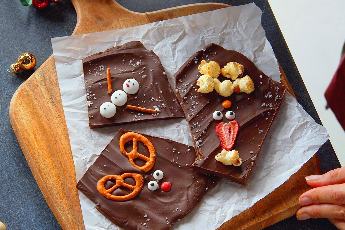 Schneemänner, Rentiere und Weihnachtsmänner aus Bruchschokolade in der Draufsicht.