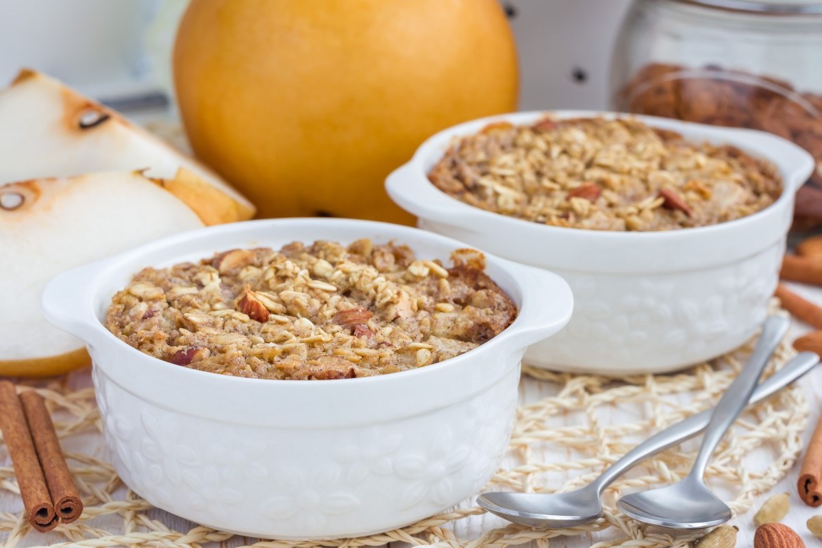 Zwei kleine Förmchen mit Ofen-Porridge. Im Hintergrund liegen frische Birnen.