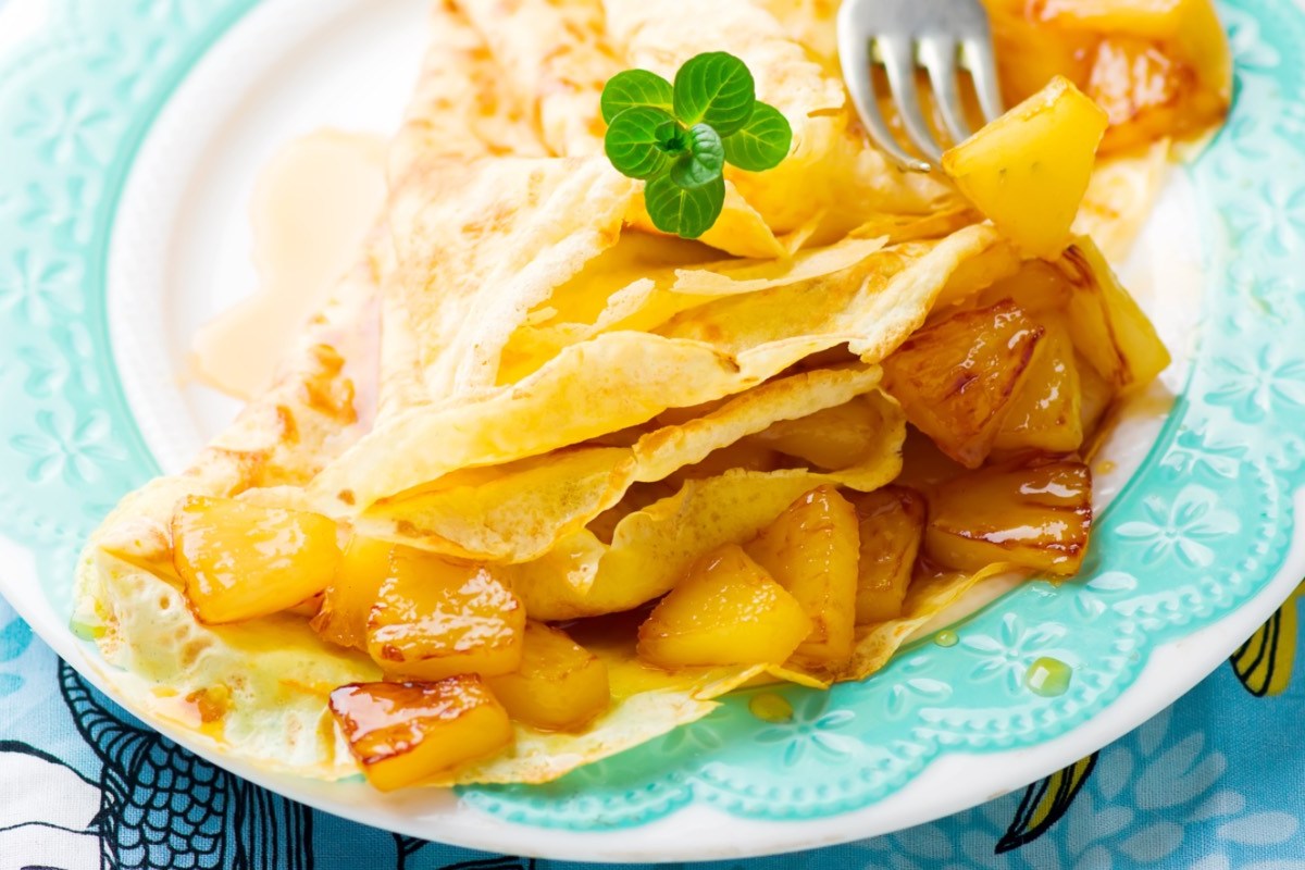 Kokoscrêpes mit karamellisierter Ananas auf einem Teller.