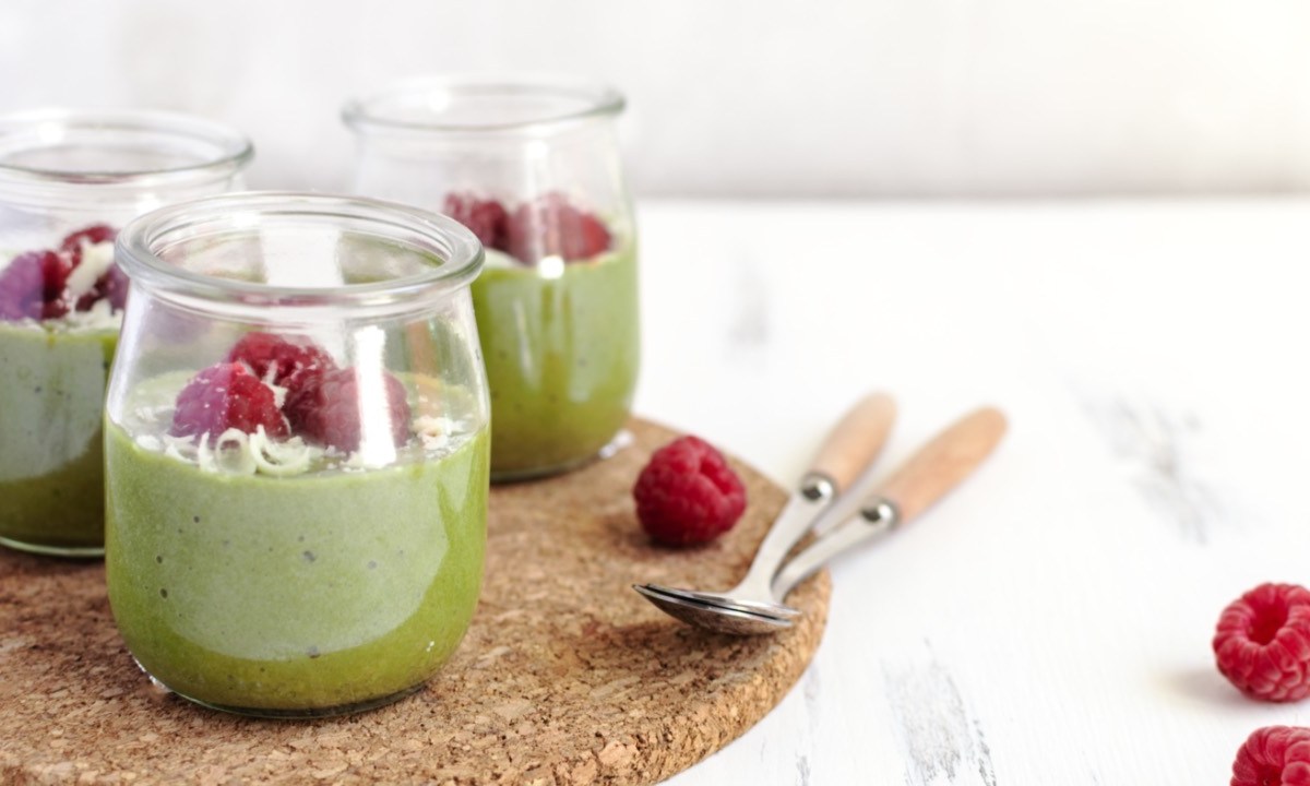 Drei Gläser Matcha-Pudding mit Himbeeren.