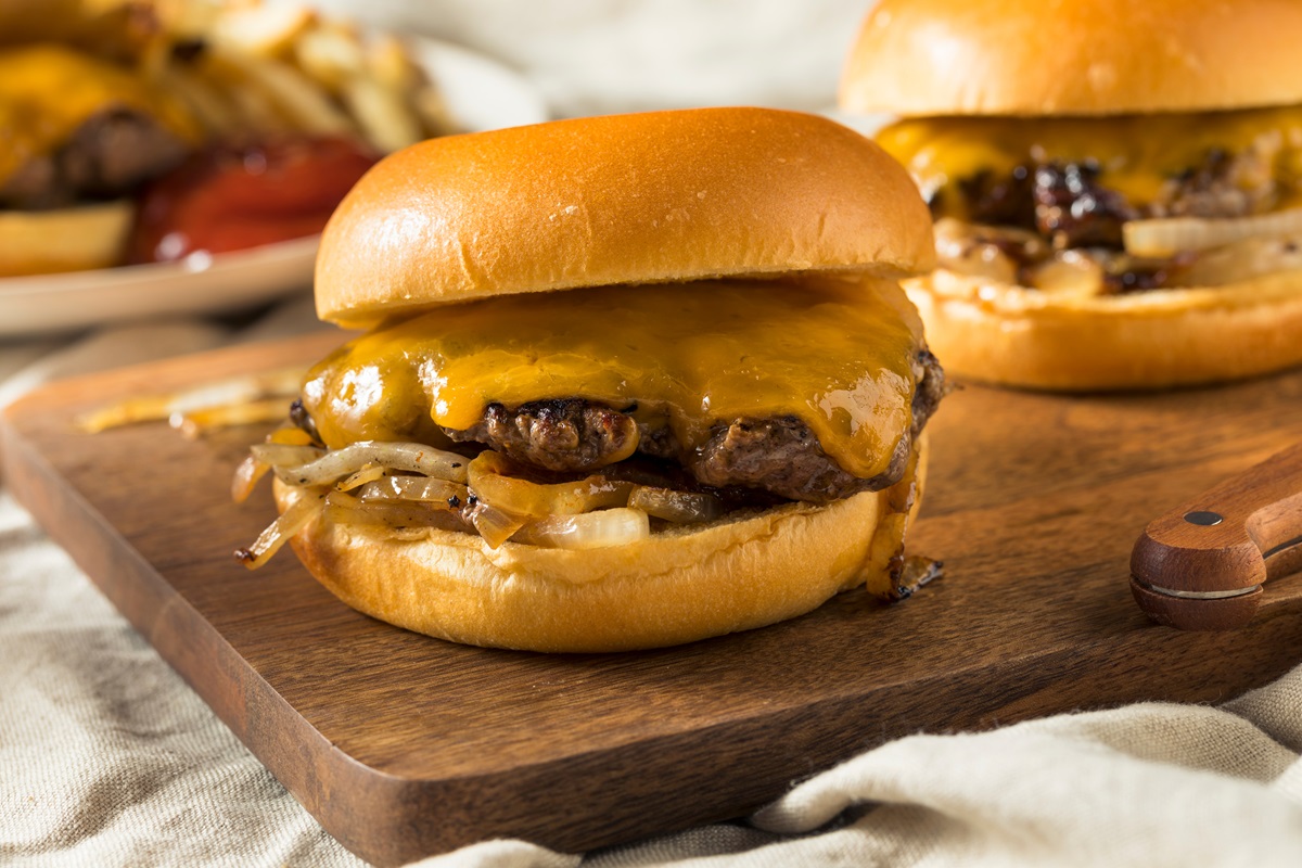 Mehrere Oklahoma Onion Burger auf einem Holzbrett.