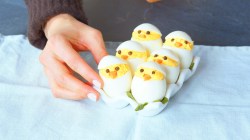 Sechs Eierküken als Oster-Fingerfood auf einem blauen Tuch.