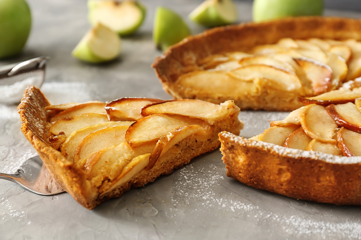 Schmand-Apfelkuchen ohne Mehl, von dem schon ein Stück entnommen wurde.