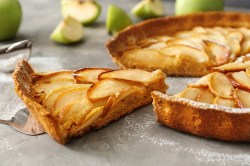 Schmand-Apfelkuchen ohne Mehl, von dem schon ein Stück entnommen wurde.