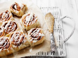 Mehrere Zimtschnecken mit Eierlikör auf Backpapier, daneben ein Tortenheber.