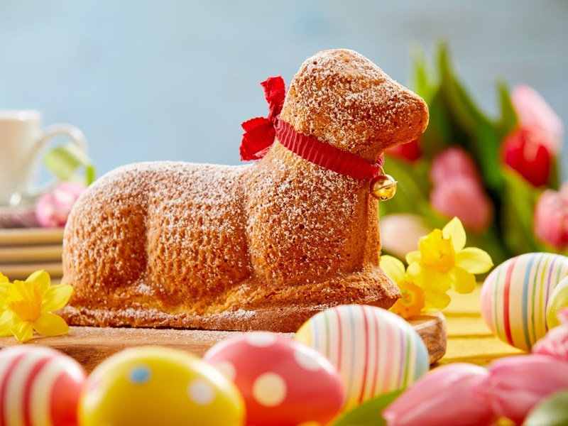 Osterlamm backen: Ein Osterlamm steht zwischen bunten Ostereiern.