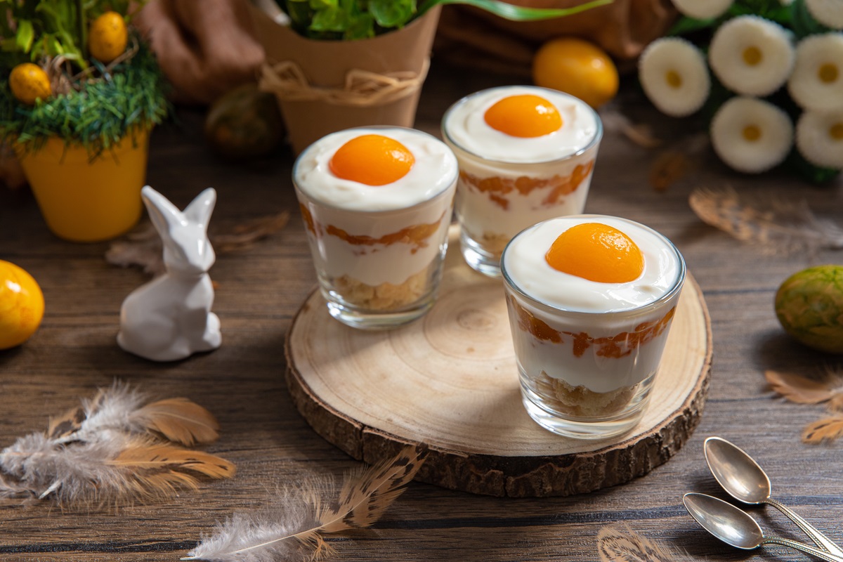 Drei Gläser mit Spiegelei-Dessert auf einem Tisch, Osterdeko daneben