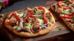 Zwei indische Pizzen auf Holzbrettern.