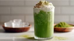 Glas Matcha Frappuccino auf einem Tisch, Schale Eiswürfel daneben
