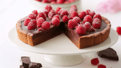 Angeschnittene Himbeer-Schoko-Tarte auf einer Etagere.