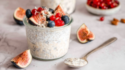 Ein Glas mit Kefir Overnight Oats, serviert mit Beeren, Feigen und Kokosraspeln.