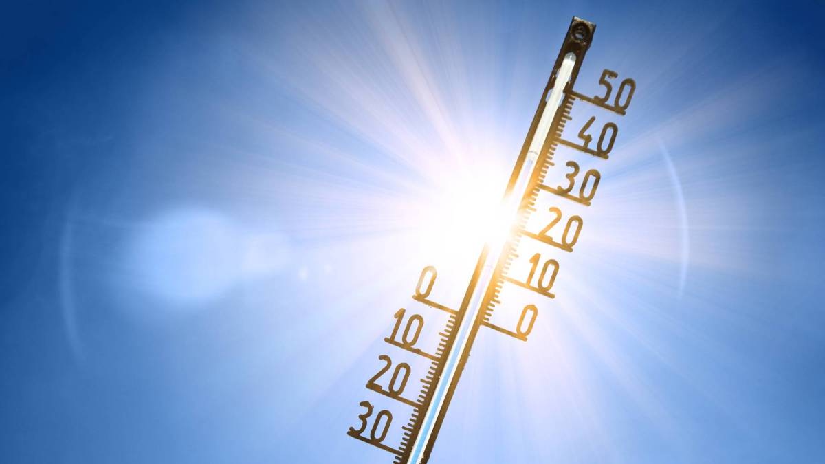 Ein Thermometer vor strahlend blauem Himmel und der Sonne. Das Bild steht metaphorisch für 